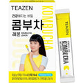 TEAZEN Kombucha Lemon — Yellow-and-white kombucha box with a printed portrait, beside an individual stick.