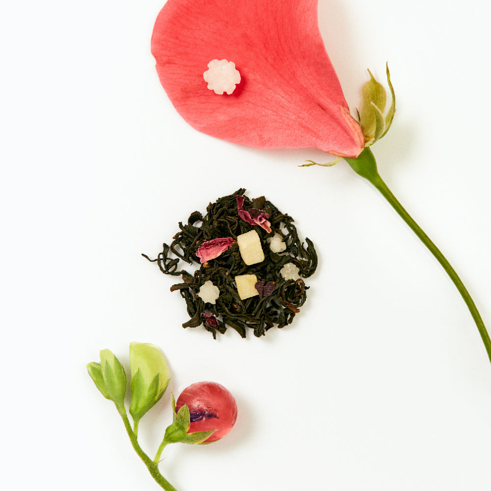 OSULLOC Camellia Forest Tea — Loose tea blend arranged beside pink petals and flower stems.