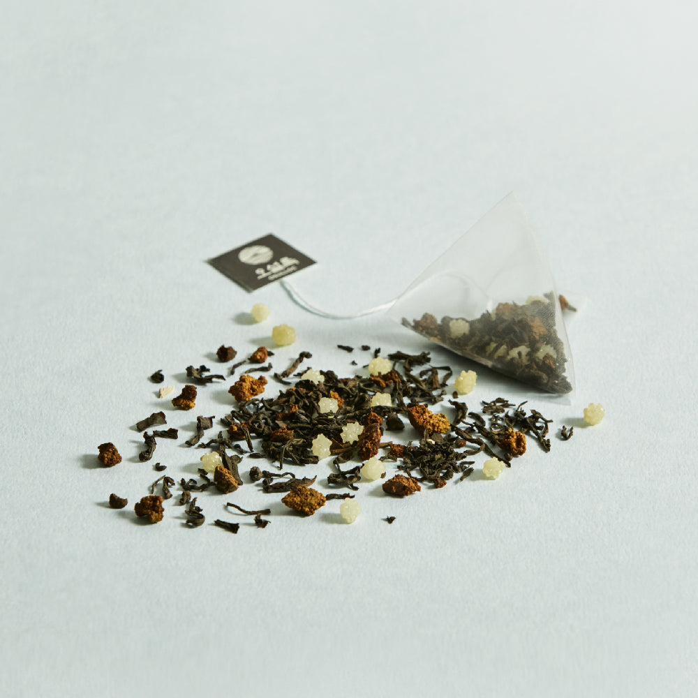 OSULLOC Moon Walk Tea — Pyramid tea bag beside a scattered loose tea blend.