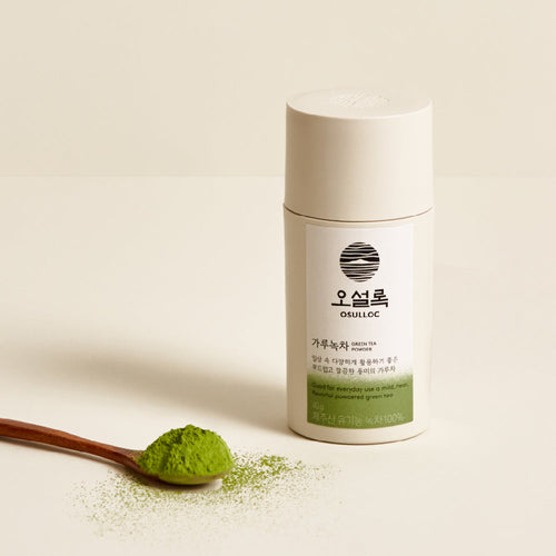 OSULLOC Jeju Green Tea Powder 40 g — Cream cylindrical container beside a wooden spoon of green tea powder.