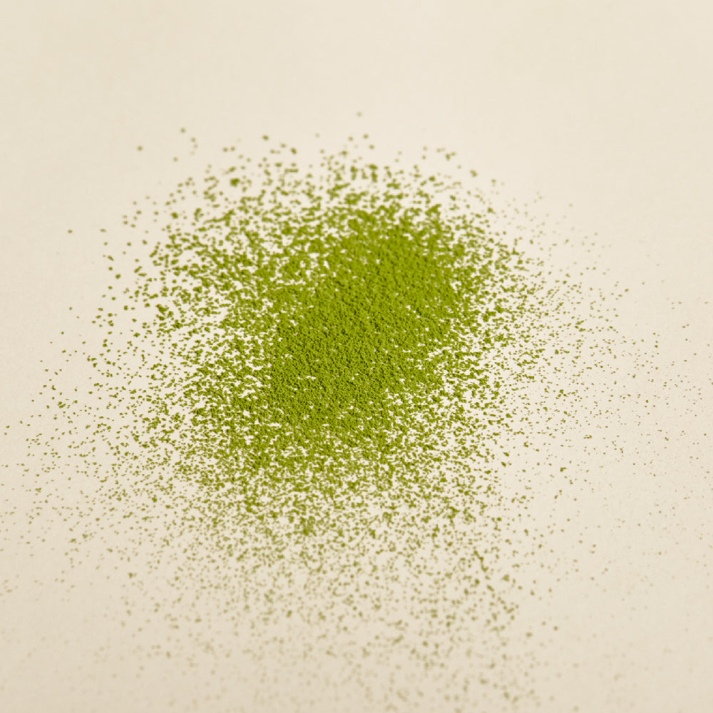 OSULLOC Jeju Green Tea Powder 40 g — Fine green tea powder scattered on a cream surface.