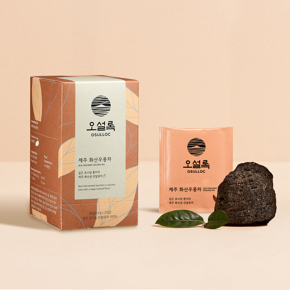 OSULLOC Jeju Volcanic Oolong Tea — Caja de color terracota y sobre de té junto a una roca oscura.