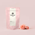 OSULLOC Wedding Green Tea — Pink pouch beside two pink roses.