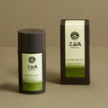 OSULLOC Premium Jeju Matcha Powder 40 g — Dark cylindrical matcha container and matching box on an olive surface.