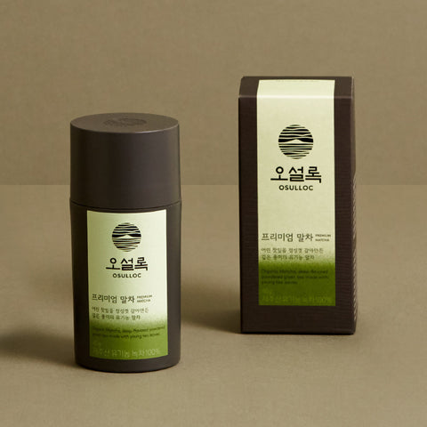 OSULLOC Premium Jeju Matcha Powder 40 g — Dark cylindrical matcha container and matching box on an olive surface.
