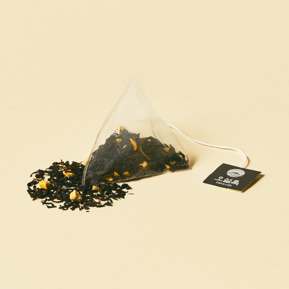 OSULLOC Signature Earl Grey — Pyramid tea bag beside a dark loose blend on yellow.