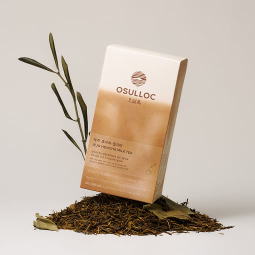 OSULLOC Jeju Hojicha Milk Tea — Cream-and-brown Hojicha Milk Tea box standing on loose roasted tea.