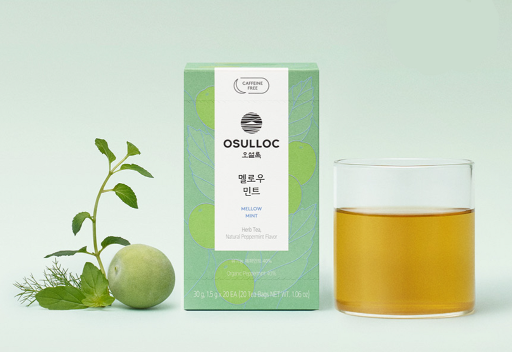 OSULLOC Herbal Tea Life Set — Green mint box beside herbs, green fruit and a glass of golden infusion.