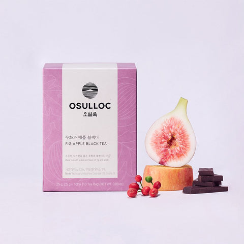 OSULLOC Fig Apple Black Tea — Pink box beside a cut fig on an apple slice, red berries and chocolate pieces.