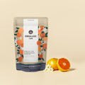 OSULLOC Tangerine Blossom Oolong Tea — Bolsa con motivos de cítricos junto a cítricos enteros y partidos y flores blancas.