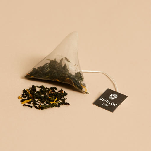 OSULLOC Tangerine Blossom Oolong Tea — Bolsita piramidal junto a té suelto y una etiqueta negra de OSULLOC.