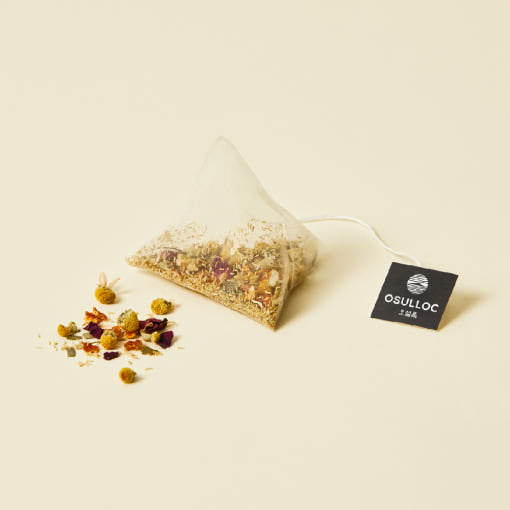 OSULLOC Chamomile Blend — Pyramid tea bag beside a small pile of dried flowers and fruit.
