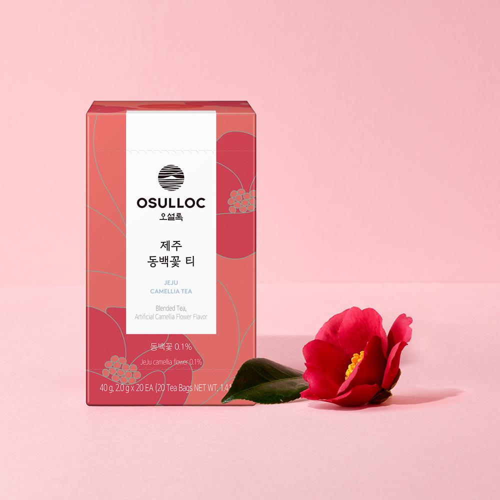 OSULLOC Jeju Camellia Tea — Caja roja junto a una flor de camelia roja y una hoja verde.
