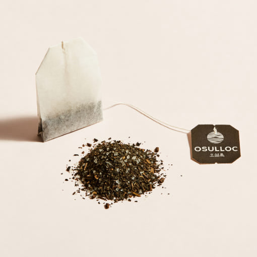 OSULLOC Jeju Camellia Tea — Paper tea bag beside loose tea and a black OSULLOC tag.