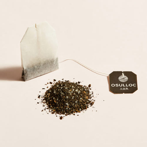 OSULLOC Jeju Camellia Tea — Paper tea bag beside loose tea and a black OSULLOC tag.