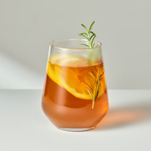OSULLOC Jeju Camellia Tea — Amber tea in a glass garnished with a citrus slice and a green sprig.