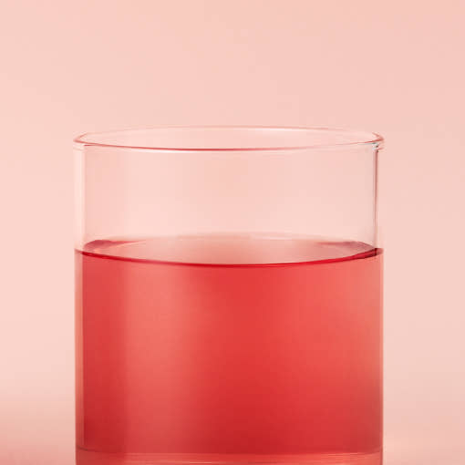 OSULLOC Sweet Hibiscus — Red infusion in a clear glass against pink.