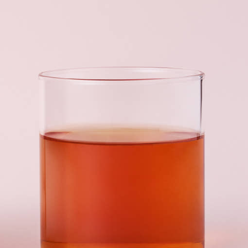 OSULLOC Marron Glace Black Tea — Té ámbar rojizo en un vaso transparente sobre fondo rosa.