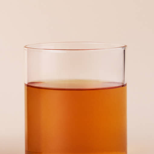 OSULLOC Fig Chocolat Black Tea — Té ámbar en un vaso transparente sobre fondo melocotón claro.