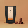 OSULLOC Jeju Volcanic Rock Tea — Bolsa oscura con etiqueta naranja junto a pequeñas rocas porosas.