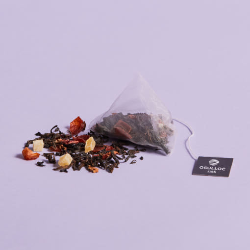 OSULLOC Peach Papaya Black Tea — Pyramid tea bag and loose blend with dried fruit on purple.