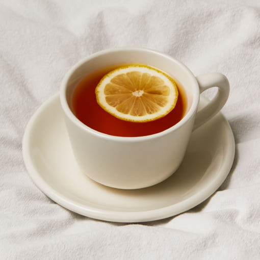 OSULLOC Rooibos Moonlight — White cup of amber infusion with a lemon slice on pale fabric.