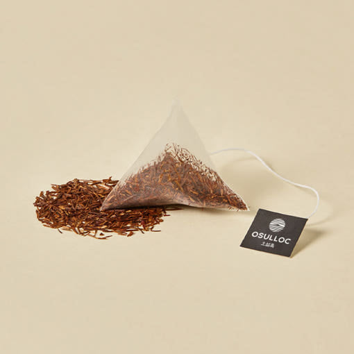 OSULLOC Rooibos Moonlight — Pyramid tea bag beside loose reddish-brown rooibos.