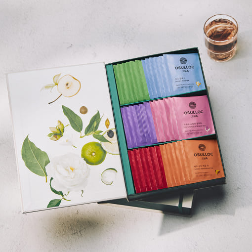 OSULLOC Tea Variation O Gift Set — Overhead view of an open illustrated gift box beside a glass of tea.