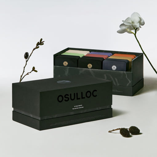 OSULLOC Tea Edition Heritage Gift Set — Cofres Heritage verde oscuro, abierto y cerrado, junto a flores delicadas.