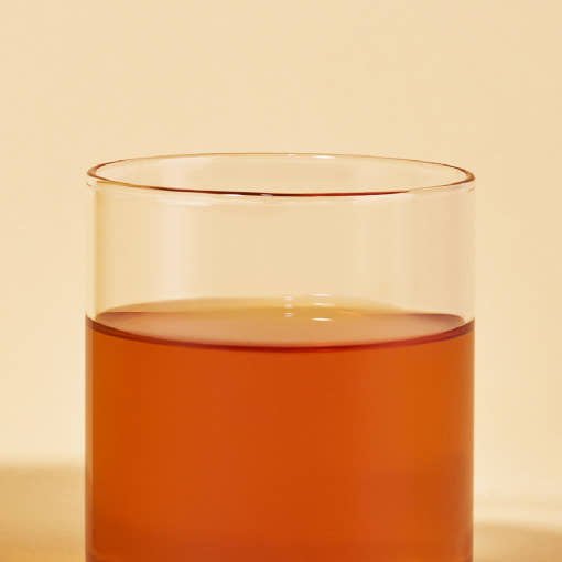 OSULLOC Vanilla Honey Black Tea — Amber tea in a clear glass against warm yellow.