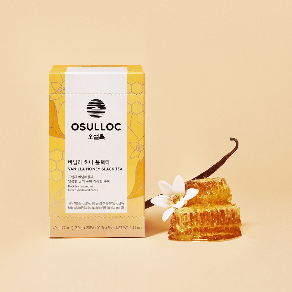 OSULLOC Vanilla Honey Black Tea — Caja amarilla de Vanilla Honey junto a panal de miel, una vaina de vainilla y una flor blanca.