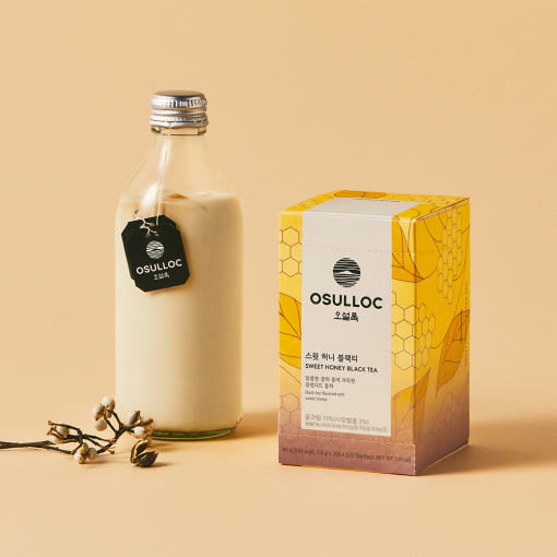 OSULLOC Sweet Honey Black Tea — Caja junto a una botella de cristal con una bebida cremosa y la etiqueta de una bolsita de OSULLOC.