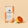 OSULLOC Tangerine Blossom Tea — Orange-and-white box beside a halved citrus fruit and white flowers.