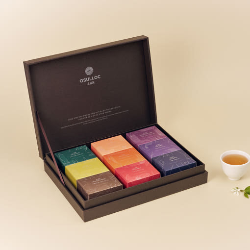 OSULLOC Premium Tea Collection 90 — Open dark gift box with small colourful tea boxes beside a cup.
